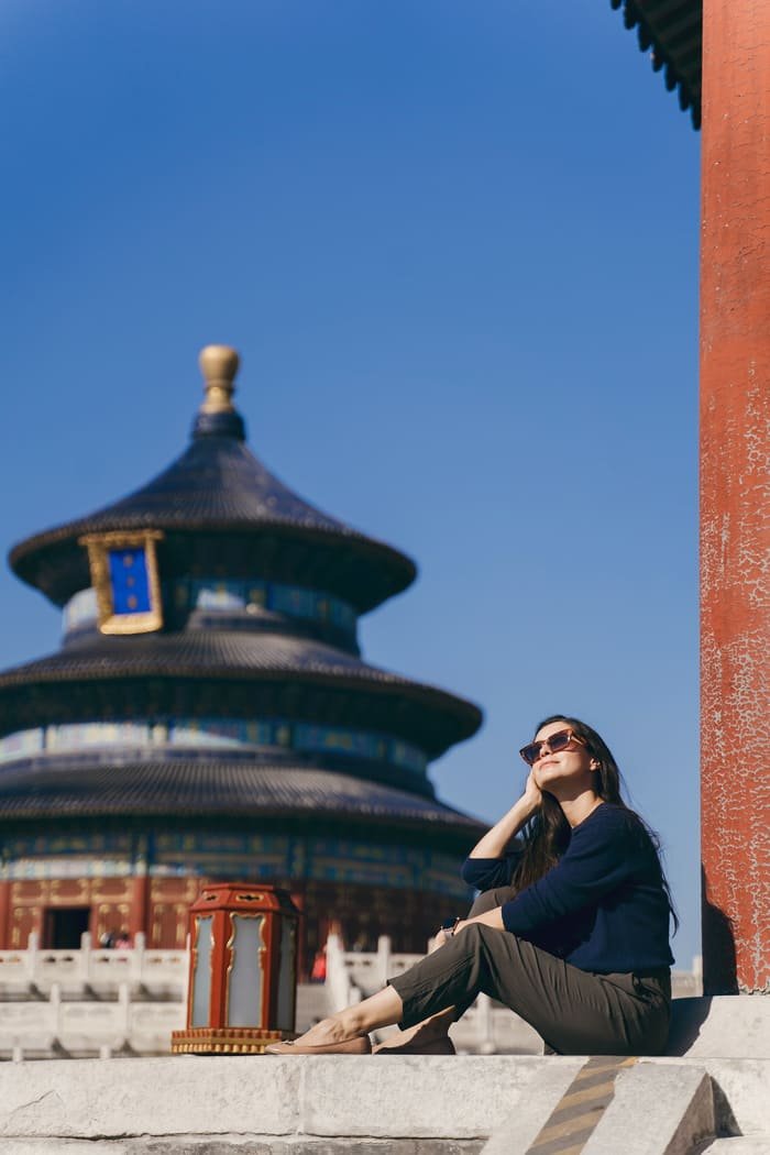 Chica turista en china, con un templo en la parte de atras de fondo