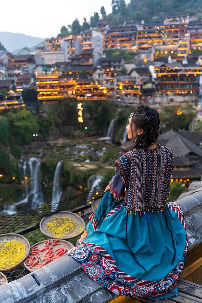 Chica observando la ciudad de Lijiang al atardecer desde lo alto